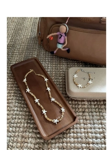 Detail of starfish beaded necklace and bracelet set on a wooden tray with boho vibe