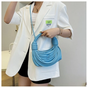 Dettaglio di borsa a tracolla blu intrecciata con design a corda tenuta da modella
