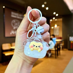 Detail of a mini yellow dog keychain with white lobster clasp and a small white bell