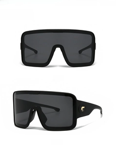 Detail view of oversized black mask sunglasses with gold star and letter temple accents