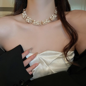 Close-up of elegant pearl and rhinestone choker necklace worn by a model in a suit