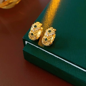 Macro shot of gold hoop earrings with green square gems and pavé zircon stones