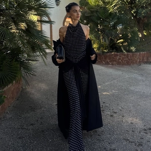 Elegant black halter polka dot dress with long black coat in a stylish outdoor street view