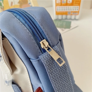 Detailed close-up of blue and beige fabric bag featuring silver zipper and stitching