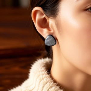 Close-up of geometric triangle stud earrings with grey marble texture and black edges