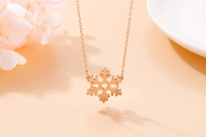Detailed view of a rose gold snowflake pendant necklace on an elegant background
