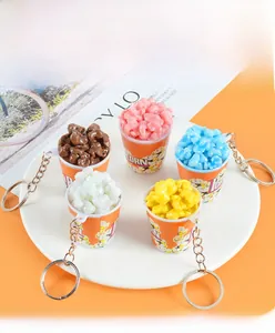 Top view of five colorful miniature popcorn bucket keychains on a white ceramic plate