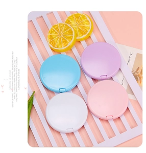 Macro shot of macaron colored foldable round pocket mirrors on a purple striped tray