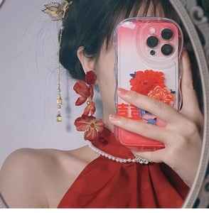 Detail of red rose earrings and golden tassel hair pin for a classic Chinese wedding style
