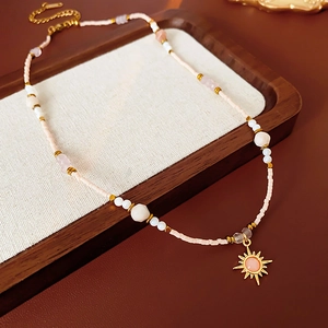 Detailed macro view of 18K gold plated sunflower pendant and pink beaded chain