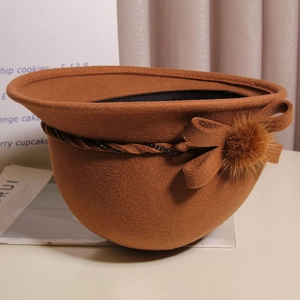Detailed close-up of brown wool felt cloche hat with mink fur ball and bow detail