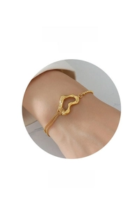 Detailed shot of irregular hollow heart gold bracelet with layered chain on wrist