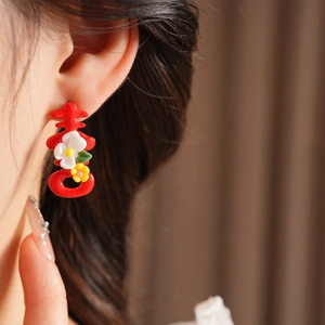Close-up of red Double Happiness character earrings with small floral details on model
