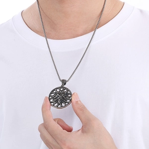 Close-up of men's stainless steel sun god face pendant necklace worn on a white t-shirt