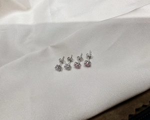 Macro detail of classic four-prong silver earrings with pink and white cubic zirconia