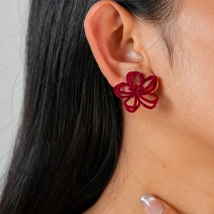 Gros plan d'une boucle d'oreille fleur floquée bordeaux sur une femme