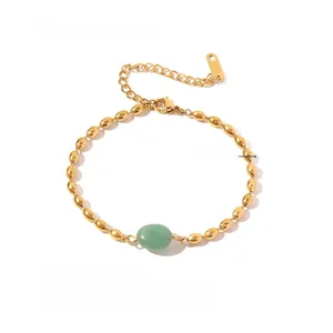 Detail of a vintage gold beaded bracelet with an oval green stone and adjustable chain