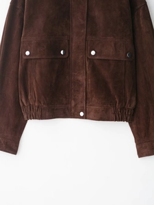 Detail of dark brown suede jacket featuring metallic snap buttons and elastic hemline