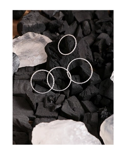 Close-up of four thin S925 sterling silver textured rings on natural charcoal and crystal