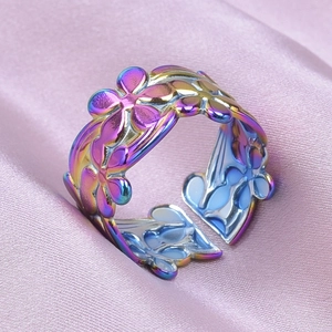 Macro shot of rainbow gradient flower hollow ring on soft pink silk fabric background