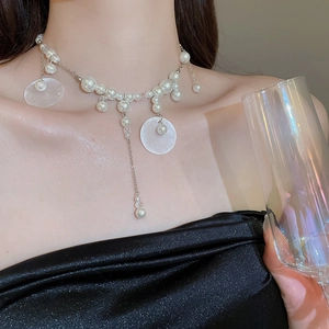 Close-up of elegant pearl and shell tassel necklace with polished silver chain