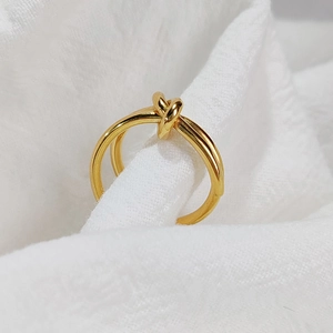 Macro shot of a 14K gold-plated stainless steel knot ring on textured fabric
