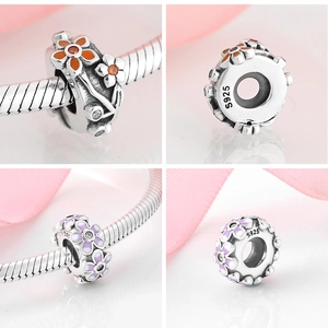 Détail macro de charmes en argent S925 avec fleurs en émail violettes et orange