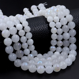 Strands of iridescent white moonstone beads for DIY jewelry on black leather background