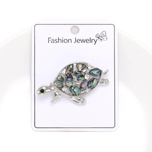 Detail of silver turtle brooch featuring colorful abalone shell and white rhinestones