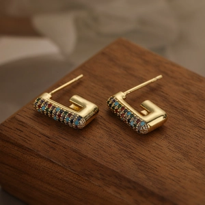 Dettaglio di orecchini placcati oro a forma di U con zirconi cubici multicolore