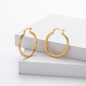 Detail showing the S925 hallmark on gold twisted hoop earrings with textured finish