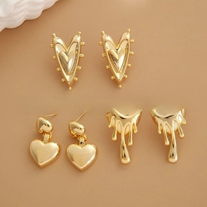 Detail showing three styles of vintage 24K gold-plated heart earrings on a warm brown background