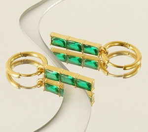 Detailed macro view of gold hoop earrings with green zircon emerald-cut rectangle pendants
