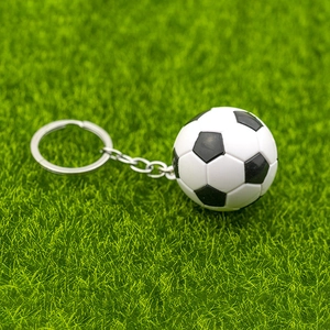 Gros plan d'un mini porte-clés de football noir et blanc sur un fond d'herbe verte