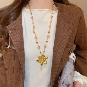 Détail du collier fleur dorée vintage avec perles colorées porté par un mannequin