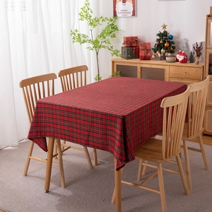 Classic red and green plaid Christmas tablecloth with tassels on a wooden dining table