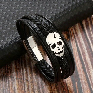 Detail of a multi-layer black braided leather bracelet with a silver skull and magnetic clasp