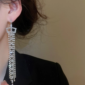 Detail of silver long tassel earrings with sparkling zircon crystals on elegant model