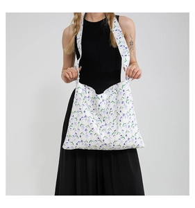 Detail of floral canvas tote bag showing blue-purple print and wide shoulder strap