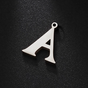 Polished titanium steel letter A pendant with sparkling stones on black background