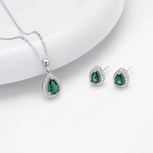 Close-up of silver jewelry set featuring emerald green teardrop stones and zircon accents