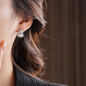 Macro view of gold-plated silver needle gourd earring with zirconia on a model's ear