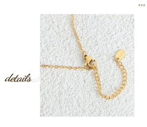 Macro detail of the lobster clasp and stainless steel extension chain on gold necklace