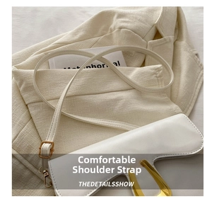 Detail of white leather saddle bag showing golden U-shaped buckle and fine strap texture