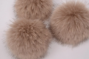 Vue détaillée de trois pompons en fausse fourrure marron pour un bonnet d'hiver en tricot