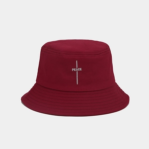 Detailed white PEACE embroidery on dark red cotton twill bucket hat texture
