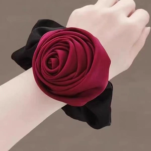 Elegant burgundy silk rose hair scrunchie worn on wrist with soft lighting detail