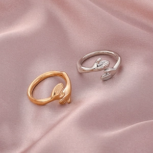 Detailansicht der gold- und silberfarbenen Umarmungsringe auf rosa Satinstoff