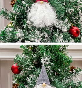 Close-up of red and grey faceless Christmas gnome ornaments hanging on a snowy tree