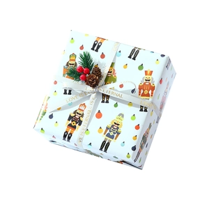Blue Christmas gift box with nutcracker pattern, white ribbon and festive pine cone decor